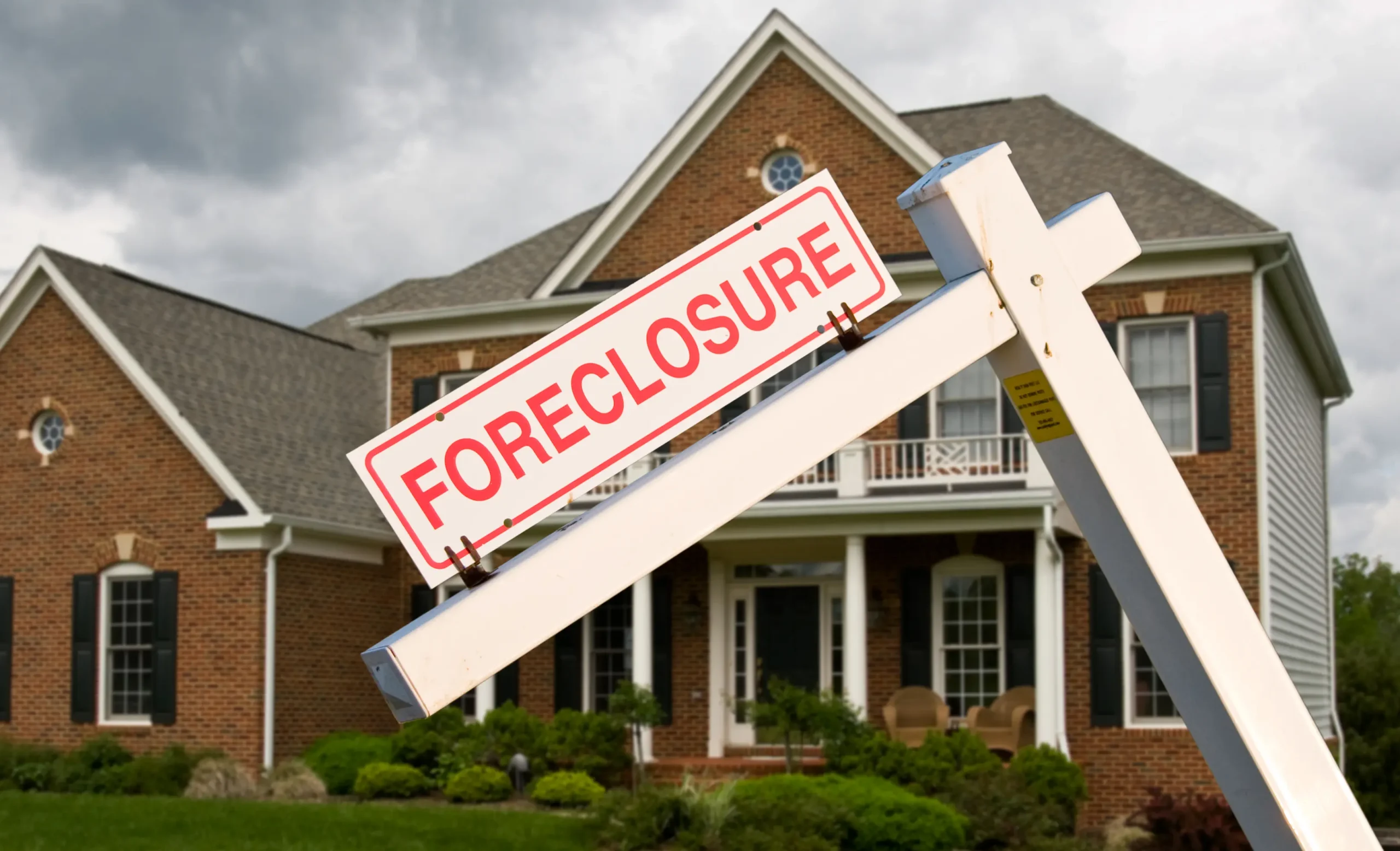 Foreclosure sign in front of a brick suburban home, representing the challenges Dallas homeowners face and the urgency of selling before foreclosure