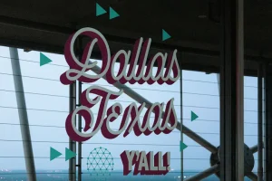 Decorative sign reading ‘Dallas Texas Y’all’ with a city backdrop, representing local Dallas culture and community